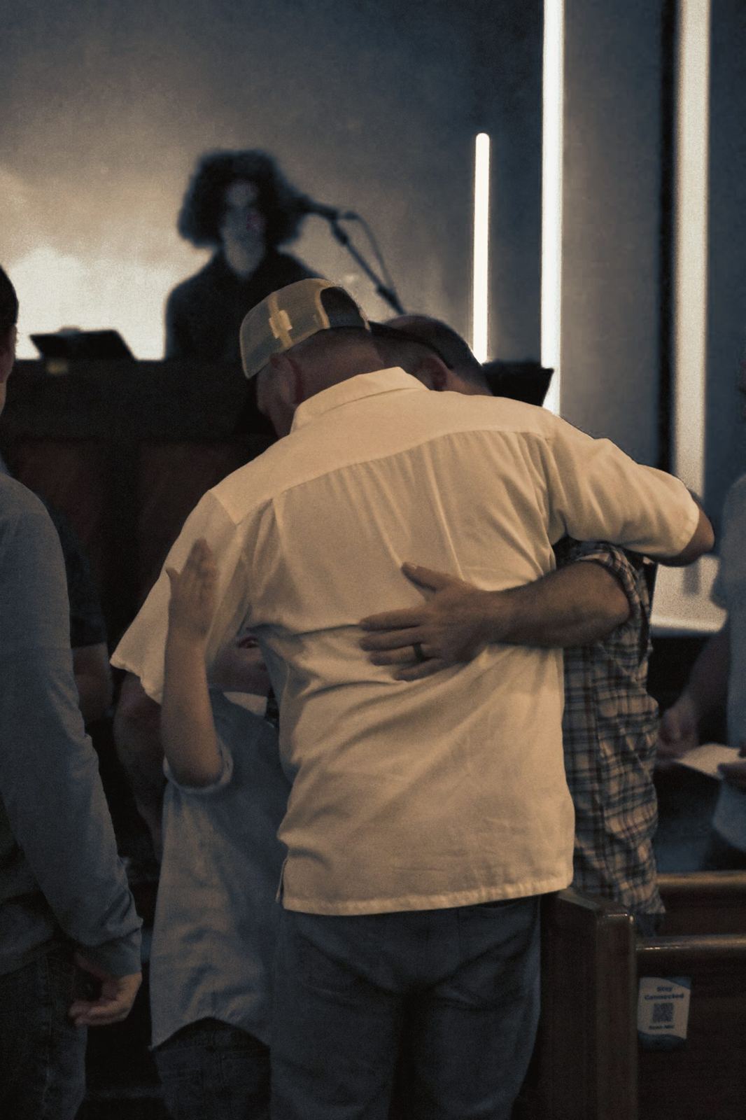 Two men embracing in a hug near the stage after a service