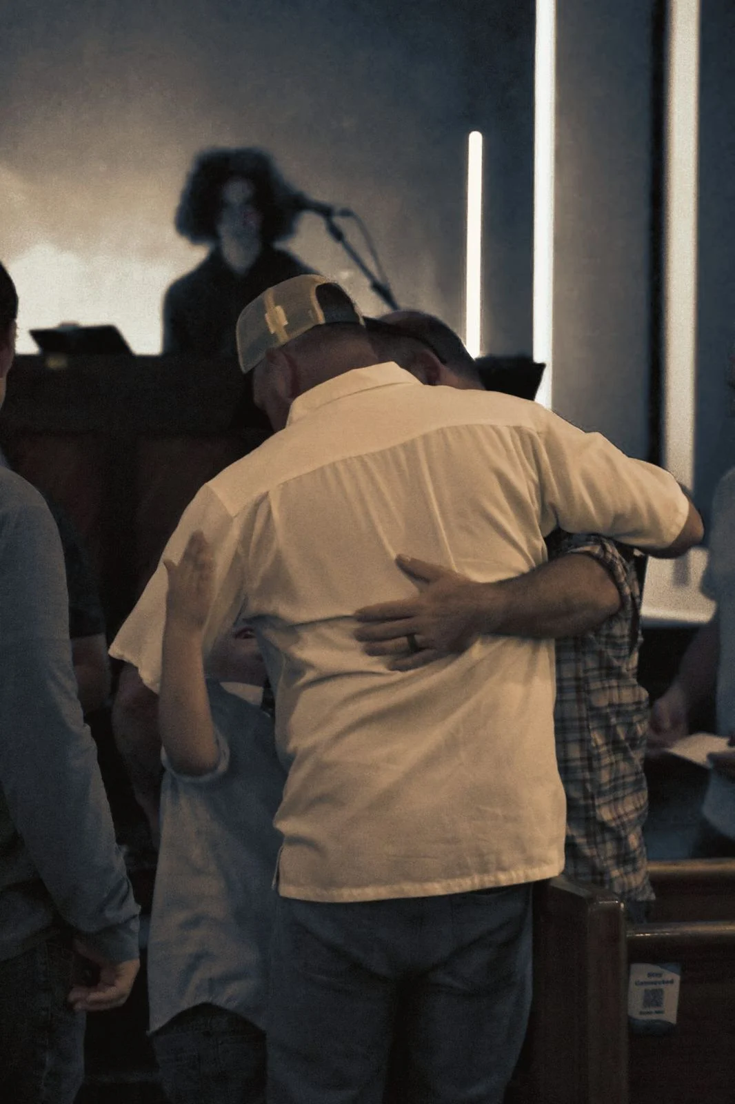 Two men embracing in a hug near the stage after a service