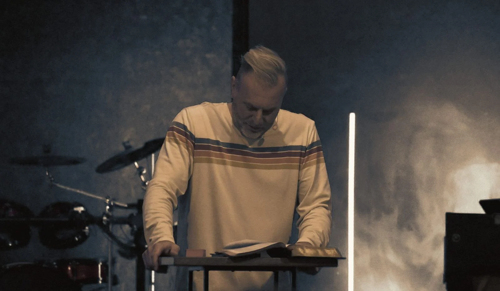 A speaker reading from the Bible on stage during a Sunday message
