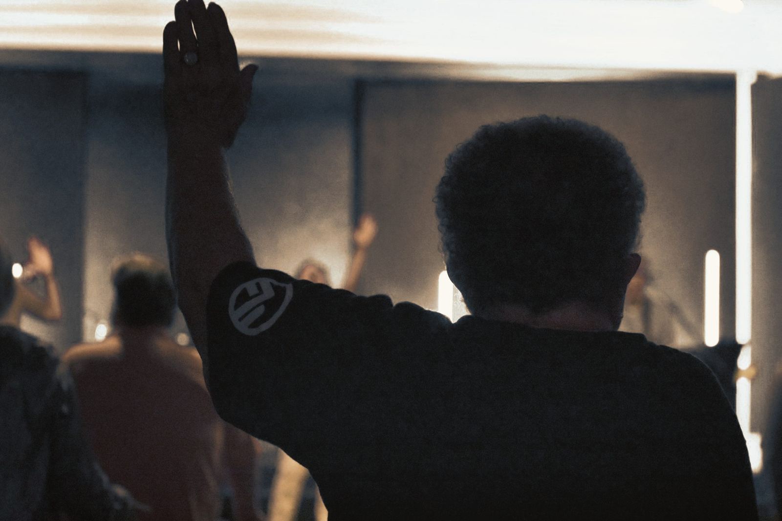 A worshiper with a hand raised during Sunday worship