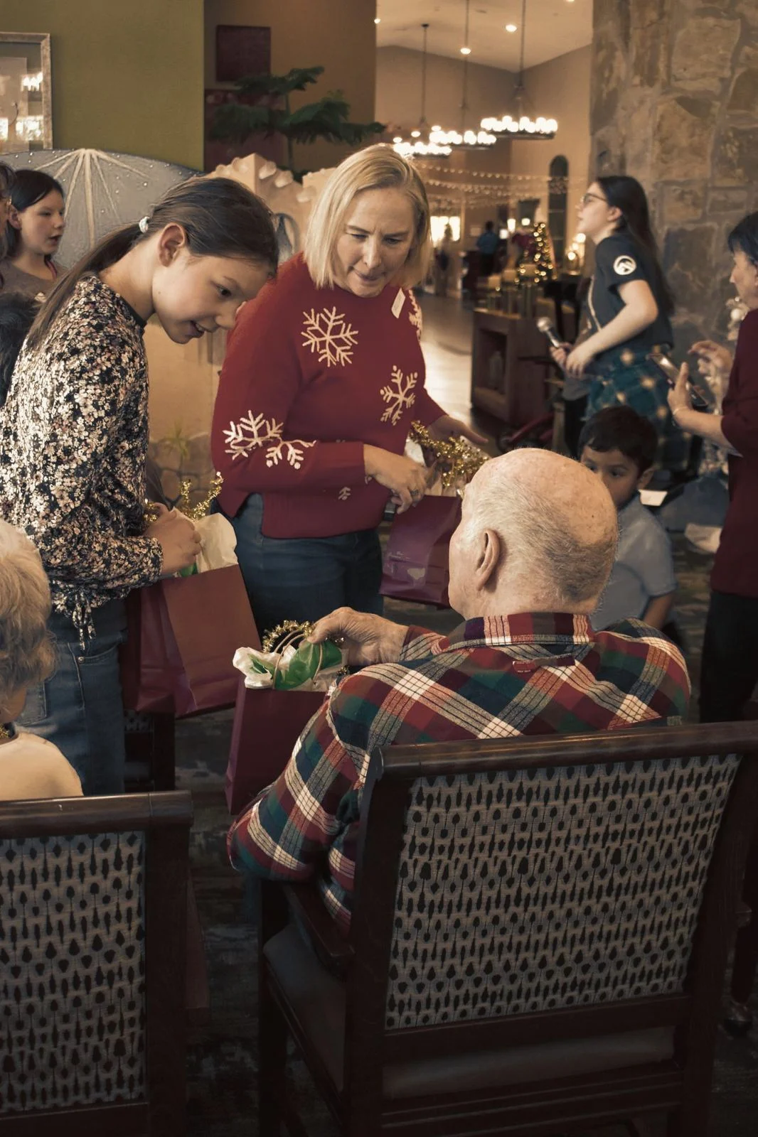 A church member in a red sweater handing out Christmas gifts to seniors