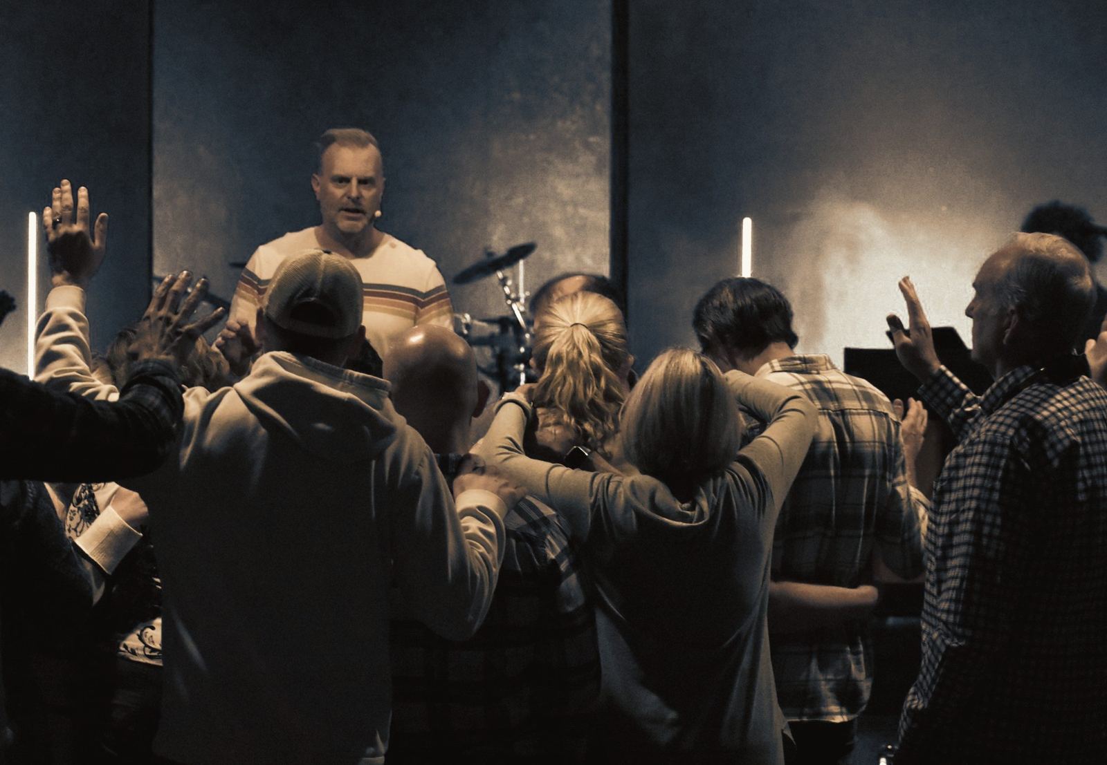 Church members laying hands on one another and praying near the stage