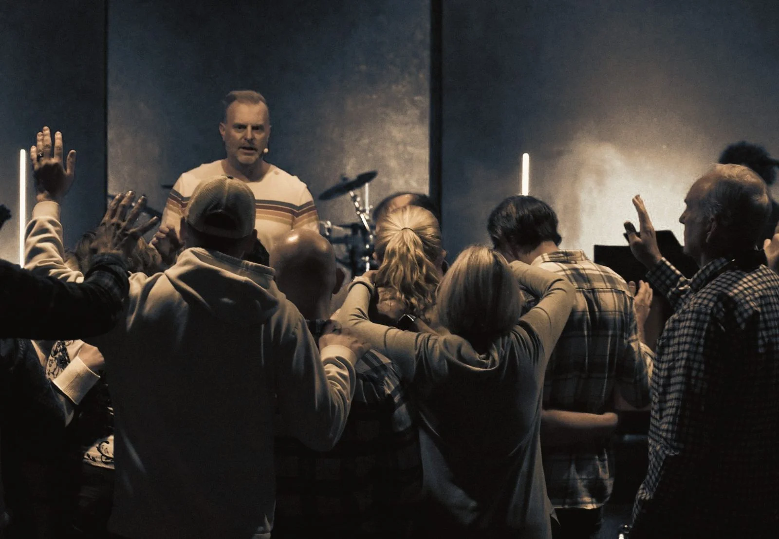 Church members laying hands on one another and praying near the stage