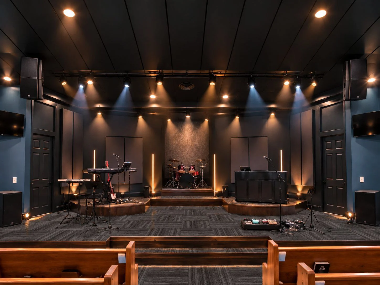 Rendering of the renovated sanctuary: dark timber ceiling, slate walls, warm stage lights and wooden pews