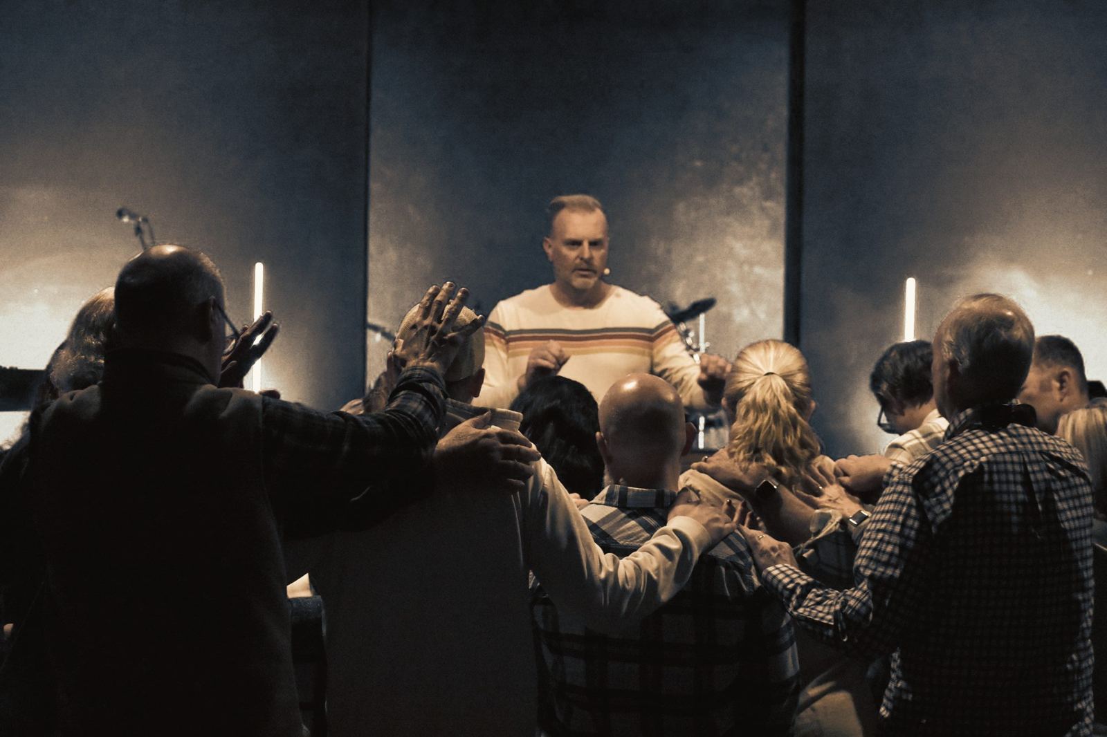Church members gathered near the stage, praying together with hands on shoulders
