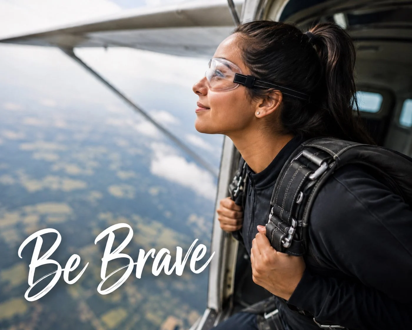A woman looking out the open door of a small plane over the